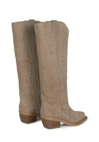Botas de estilo occidental hasta la rodilla en suave ante beige, con intrincados patrones de costura y un tacón apilado para mayor estabilidad.