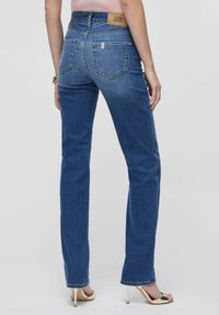 Tumesinised teksad kõrge vöökohaga, sirgete sääreosadega ja kaubamärgiga nahast plaastriga tagaküljel. Omavad kahte tagataskut ja peent pleekimist.