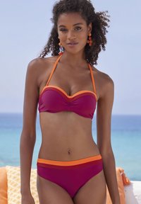 Violetinis bikinis su oranžiniais akcentais; paminkštinta viršutinė dalis turi išlenktą dizainą. Apačios turi atitinkamą spalvų schemą ir plačią juostą.