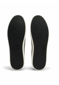 Black rubber shoe soles with textured surface. White midsole visible around edges, featuring "TOMMY HILFIGER" branding on each sole.