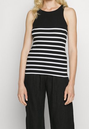 Stribet tanktop i sort og hvid med ribbet tekstur. Har en rund halsudskæring og fitted design, parret med løse sorte bukser.