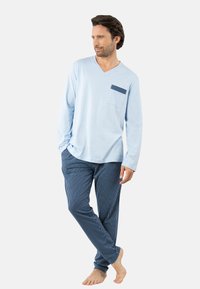 Haut bleu clair à manches longues et col en V avec une poche rayée, associé à un pantalon rayé bleu marine et blanc, coupe décontractée avec une texture douce.