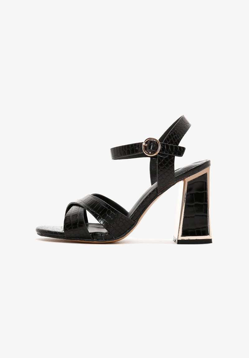 Sandale noire à talons hauts avec texture crocodile, dotée d'une boucle en métal ronde et d'un talon bloc géométrique rehaussé d'or.