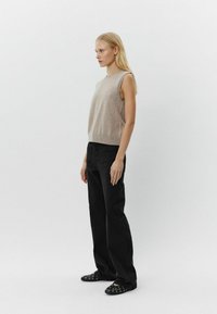 Beige ærmeløs top, sorte vide jeans og sorte flade sko med runde detaljer; glat tekstur, enkelt design og afslappet pasform.