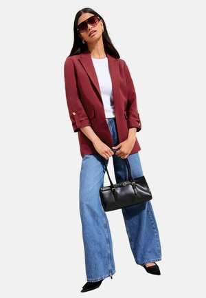 Burgundy blazer with rolled sleeves, white t-shirt, wide-leg blue jeans, black handbag, oversized dark sunglasses, sleek hair.