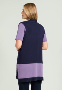 Jersey sin mangas en azul marino y lavanda, con un diseño en bloques de color y aberturas laterales. Confeccionado en un material de punto suave.