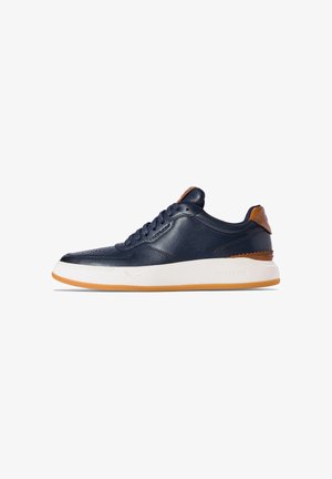 Sneaker in pelle blu con suola intermedia bianca e suola esterna in gomma naturale. Presenta dettagli marroni sul tallone e texture sulla parte laterale.