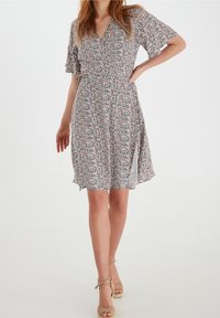 Vestido floral de tela ligera con escote en V, mangas cortas de vuelo y cintura ceñida. Los colores incluyen patrones en rosa, azul y crema.