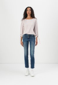 Lys rosa stripete langermet topp med rulle cuffs, kombinert med blå skinny jeans med slitte detaljer og hvite sneakers.