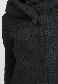 Svart texturerad kappa med huva, som har en enda knappstängning och mjukt, fluffigt tyg som framhäver värme och komfort.