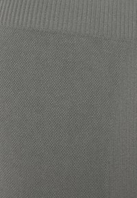 Grijze gebreide stof met een gestructureerd oppervlak en een geribd patroon aan de bovenkant. Het materiaal heeft een zachte, flexibele uitstraling.