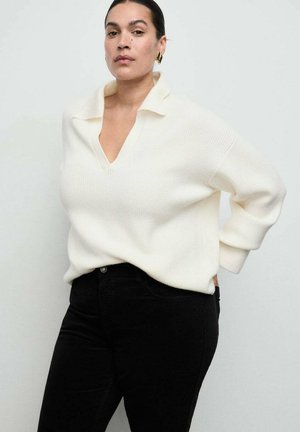 Kremowy sweter z dzianiny z głębokim dekoltem w serek i szerokim kołnierzem, połączony z czarnymi dżinsami z wysokim stanem. Charakteryzuje się prążkowaną fakturą i luźnym krojem.