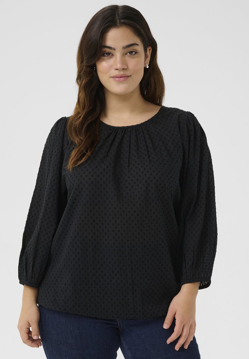 Zwarte blouse met lange mouwen in gestructureerde stof, met een gathered halslijn en pofmouwen. Heeft een subtiel stippenpatroon en een ontspannen pasvorm.