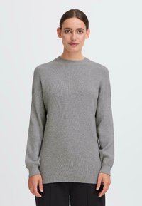 Hellgrauer Strickpullover mit Rundhalsausschnitt, fallenden Schultern und geripptem Muster. Lange Ärmel reichen bis zum Handgelenk und bieten eine entspannte Passform.