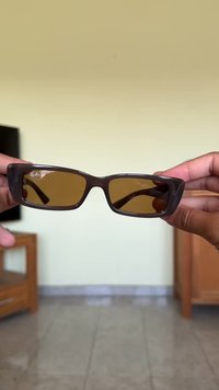 Καφέ ορθογώνια γυαλιά ηλίου με καφέ τόνωση φακών. Διαθέτουν χοντρό σκελετό και ελαφριά καμπύλη στην κορυφή. Λογότυπο εμφανές στον αριστερό φακό.