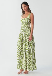 Robe maxi en vert et blanc avec un motif zèbre, dotée d'un décolleté carré, d'une taille smockée et de larges bretelles.