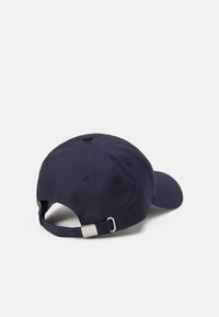 Gorra azul marino hecha de algodón, con visera curva, correa ajustable con herrajes de plata y ojales de ventilación a los lados.