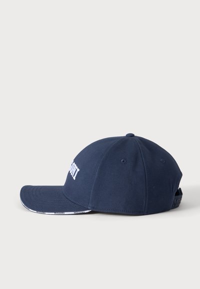 Casquette de baseball bleu marine avec texte brodé blanc sur l’avant et sangle ajustable à l’arrière sur un fond clair uni.