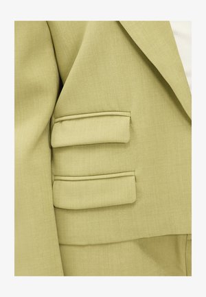 Blazer vert clair en tissu texturé, avec des revers crantés et des détails d'épaule rembourrés. Comprend trois accents rectangulaires sur les manches.