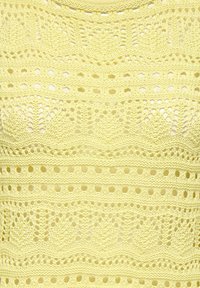 Tissu tricoté jaune présentant des motifs ajourés complexes, incluant des vagues et des losanges, avec une finition douce et texturée.