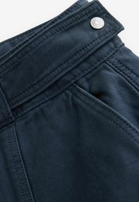 Navy blauwe broek met een gladde textuur, taps toelopend ontwerp, voorzak en een metalen knoop aan de tailleband voor sluiting.