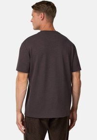 Tamsiai pilkas trumpomis rankovėmis marškinėliai su apvaliu kaklu, laisvu siluetu ir minkšta tekstūra, turintys minimalų dizainą be grafikų ar akcentų.