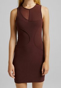 Bordové bezramínkové šaty s přiléhavým střihem, zdobené výřezy a hladkou texturou. Kulatý výstřih a minimalistický styl.
