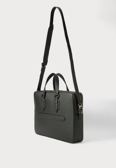 Malette en cuir noir avec poignées doubles en haut, bandoulière réglable et poche avant. Texture lisse et forme structurée.
