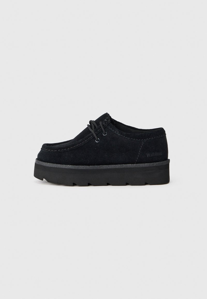 Chaussure à lacets en daim noir avec semelle épaisse à relief, hauteur basse à la cheville, avec coutures visibles sur les bords, vue de côté sur fond gris.