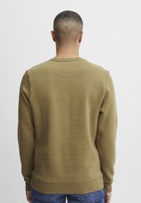 Olive green sweatshirt made of soft fabric, featuring a crew neck and ribbed cuffs. Design is simple with no visible logos or patterns.