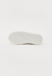 Valge jooksutossude tald koos tekstuuriga mustriga, ümarate servadega ja logo detailiga. Sile, kummimaterjal lihtsa ja minimalistliku disainiga.