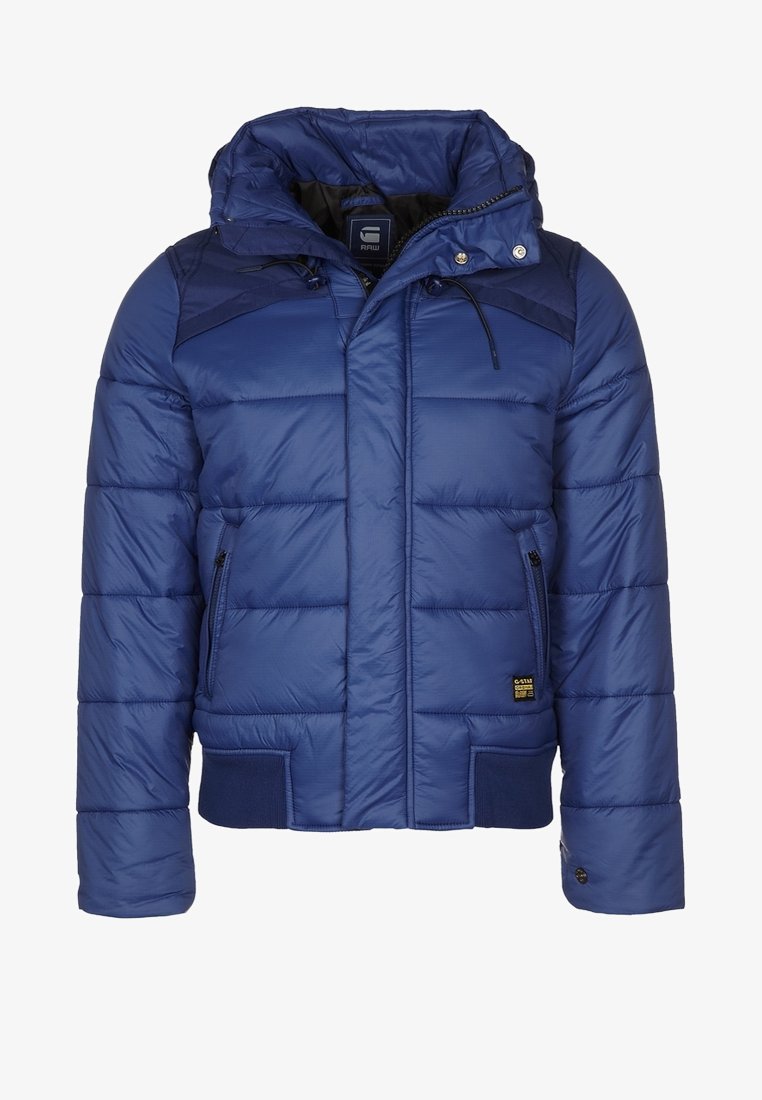 Blaue gepolsterte Winterjacke mit Kapuze, Frontreißverschluss, Reißverschlusstaschen an den Seiten, gerippte Bündchen und kleinem Markenlabel auf der Tasche.