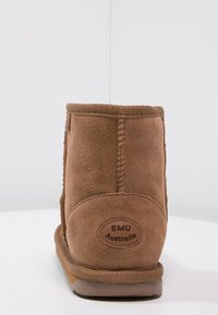 Brązowy zamszowy botek sięgający kostki z okrągłym czubkiem, detalami stębnowania oraz gumową podeszwą. Na tyle znajduje się logo EMU Australia.