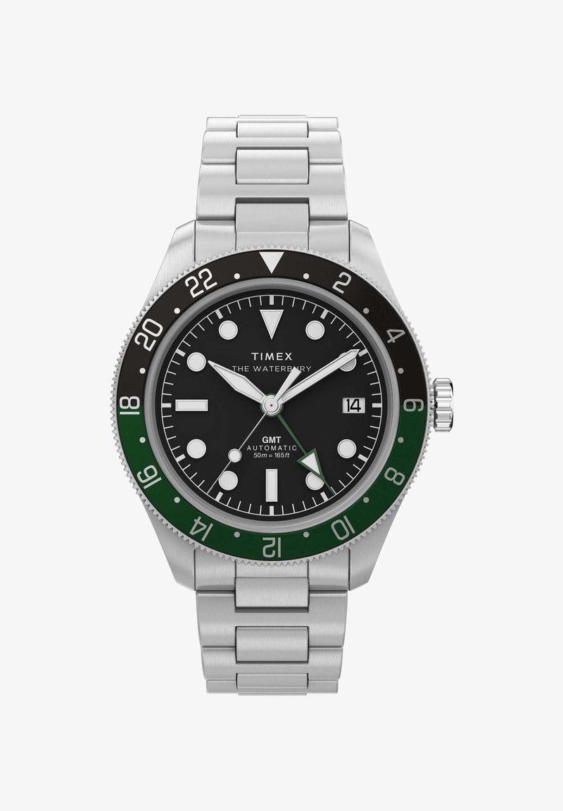 Ρολόι Timex Waterbury GMT από ανοξείδωτο χάλυβα με μαύρο καντράν, πράσινη και μαύρη στεφάνη, φωσφορίζοντες δείκτες, παράθυρο ημερομηνίας και ασημένιο μεταλλικό βραχιόλι.