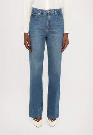 Light blue denim jeans with a high waist, wide-leg style, belt loops, and five-pocket design; matching white pointed-toe heels.