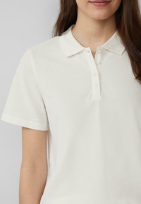 Witte polo t-shirt van een textuur katoenmix, met een kraag en een sluiting met drie knopen. Korte mouwen, klassieke pasvorm.