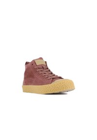 Des baskets montantes en daim rose poussière avec une semelle en caoutchouc texturé jaune, présentant un design à lacets et un patch logo sur la languette.