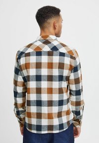 Camicia da uomo a maniche lunghe con un design a quadri multicolore, con quadrati marroni, blu navy, grigi e bianchi, realizzata in tessuto intrecciato.