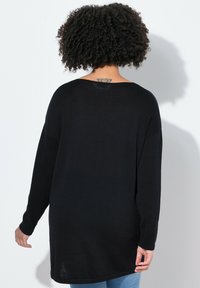 Maglione nero a maniche lunghe con una vestibilità rilassata, caratterizzato da una texture a coste e un ampio scollo, che termina poco sotto i fianchi.