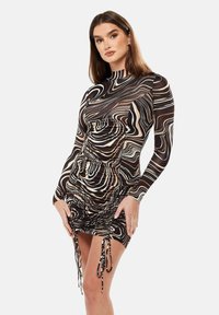 Long-sleeve dress in brown, beige, and black swirl pattern. Features ruching at the sides and adjustable tie accents at the hem.