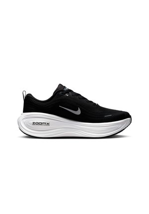 Schwarzer Sportschuh mit einer strukturierten Oberseite, weißer, gepolsterter Sohle und kontrastierender schwarzer Außensohle. Verfügt über ein reflektierendes Logo und ein Schnürsystem.