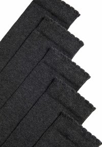 Calentadores de piernas de algodón negro con textura acanalada y bordes con picos, dispuestos en una formación apilada.