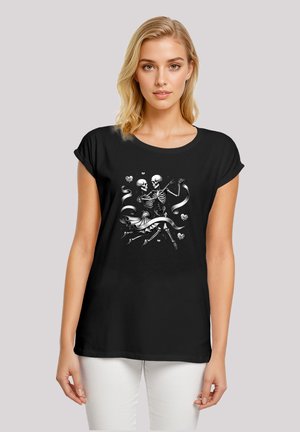 Schwarzes T-Shirt mit lockerer Passform, versehen mit einer Grafik von zwei tanzenden Skeletten umgeben von Bändern und Herzen, in Weiß und Grau gedruckt.