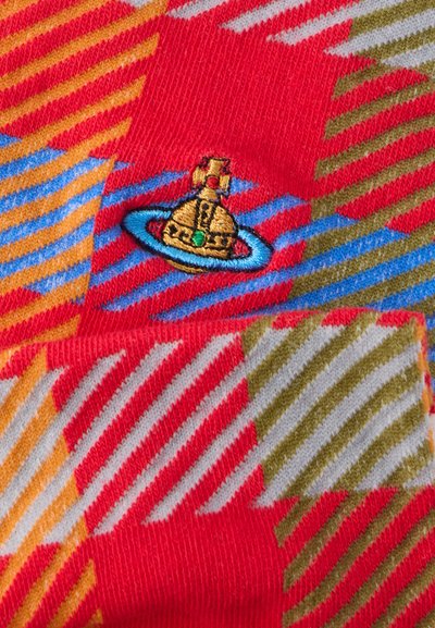 Κόκκινο ύφασμα με πολύχρωμες διαγώνιες ρίγες σε πορτοκαλί, μπλε και πράσινο. Διαθέτει χρυσή κεντημένη μπάλσα διαστημοπλοίου με πράσινη πέτρα ως διακοσμητικό.