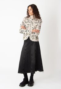 Kreemivärvi lillemustriga lühike sviiter, mis sisaldab kõrget kraed ja nööbistamist, koos musta teksariidest A-line seeliku ja mustade saapadega.