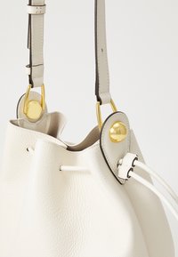 Borsa a secchiello realizzata in pelle bianca testurizzata, con hardware dorato, spallacci regolabili e chiusura con coulisse rifinita in pelle.
