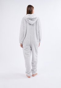 Un monos gris, esponjoso y con un patrón texturizado, que cuenta con capucha, mangas largas y puños elásticos. El diseño ofrece un ajuste holgado y una apariencia suave.