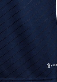 Marineblaues Gewebe mit einem diagonalen Streifenmuster aus helleren Fäden. Enthält ein Logo in der unteren rechten Ecke. Glatte Textur und athletisches Design.