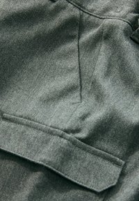 Tamno sivi materijal s glatkom teksturom, s bočnom unutarnjom džepom i suptilnim sjajem. Materijal je mekan i izgleda izdržljivo.