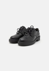 Schwarze Lederschuhe mit runden, geschlungenen Schnürsenkeln und einem niedrigen Absatz. Glatte Textur mit minimalistischem Design und dezenten Steppdetails.